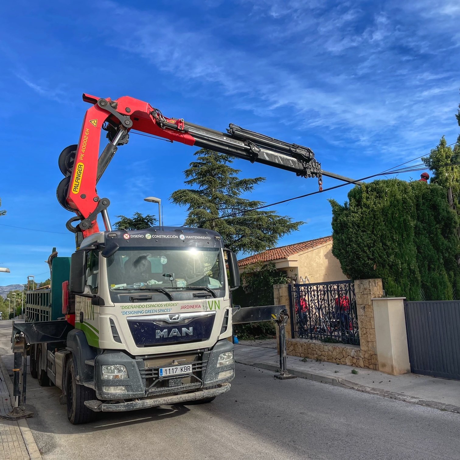 Camión grua ayudando con poda seto.